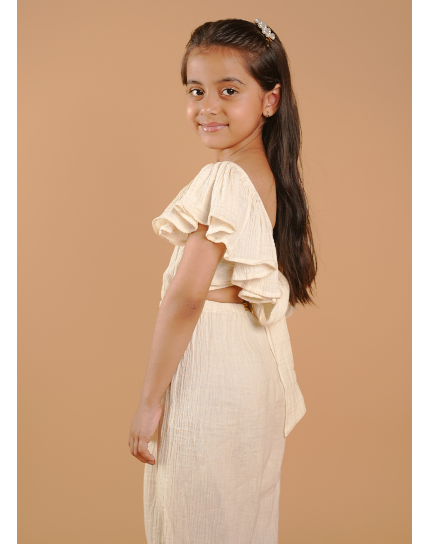 Young girl in a beige outfit standing against a beige background