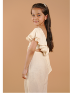 Young girl in a beige outfit standing against a beige background