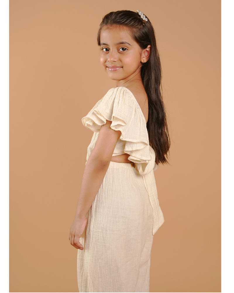 Young girl in a beige outfit standing against a beige background