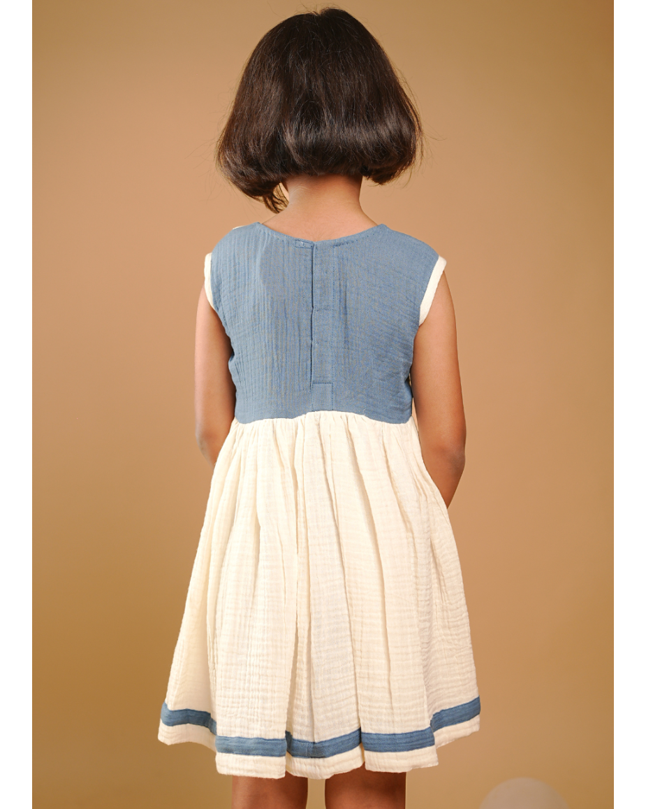 Child wearing a blue and white dress against a beige background