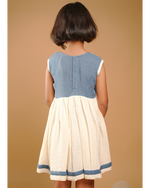Child wearing a blue and white dress against a beige background