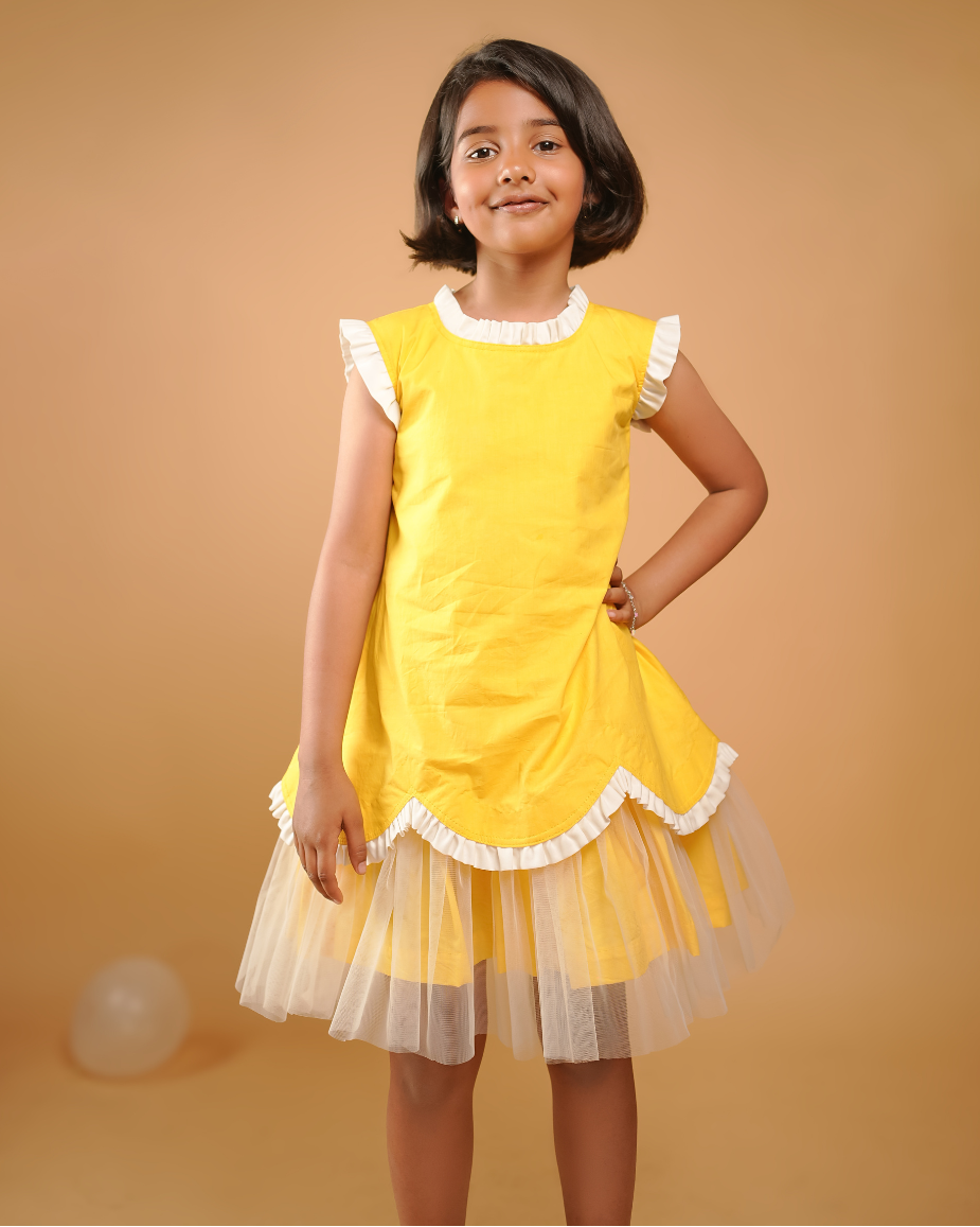 Young girl wearing a yellow dress with white trim against a beige background