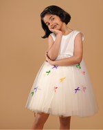 Young girl wearing a white dress with colorful designs on a beige background