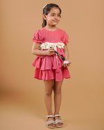 Young girl in a pink dress holding a white flower against a beige background