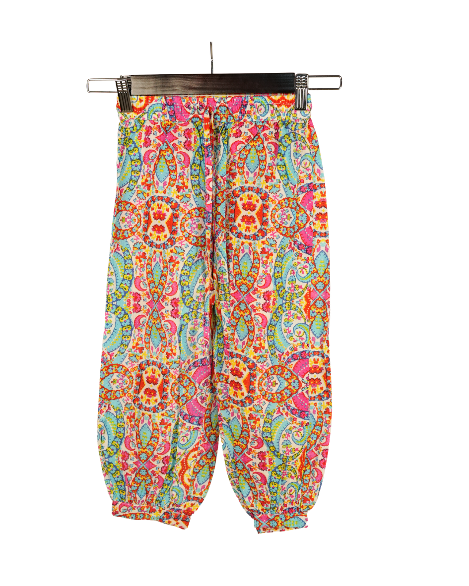 Colorful patterned pants hanging on a rack against a white background