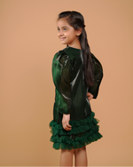 Young girl wearing a green dress with ruffled skirt against a beige background