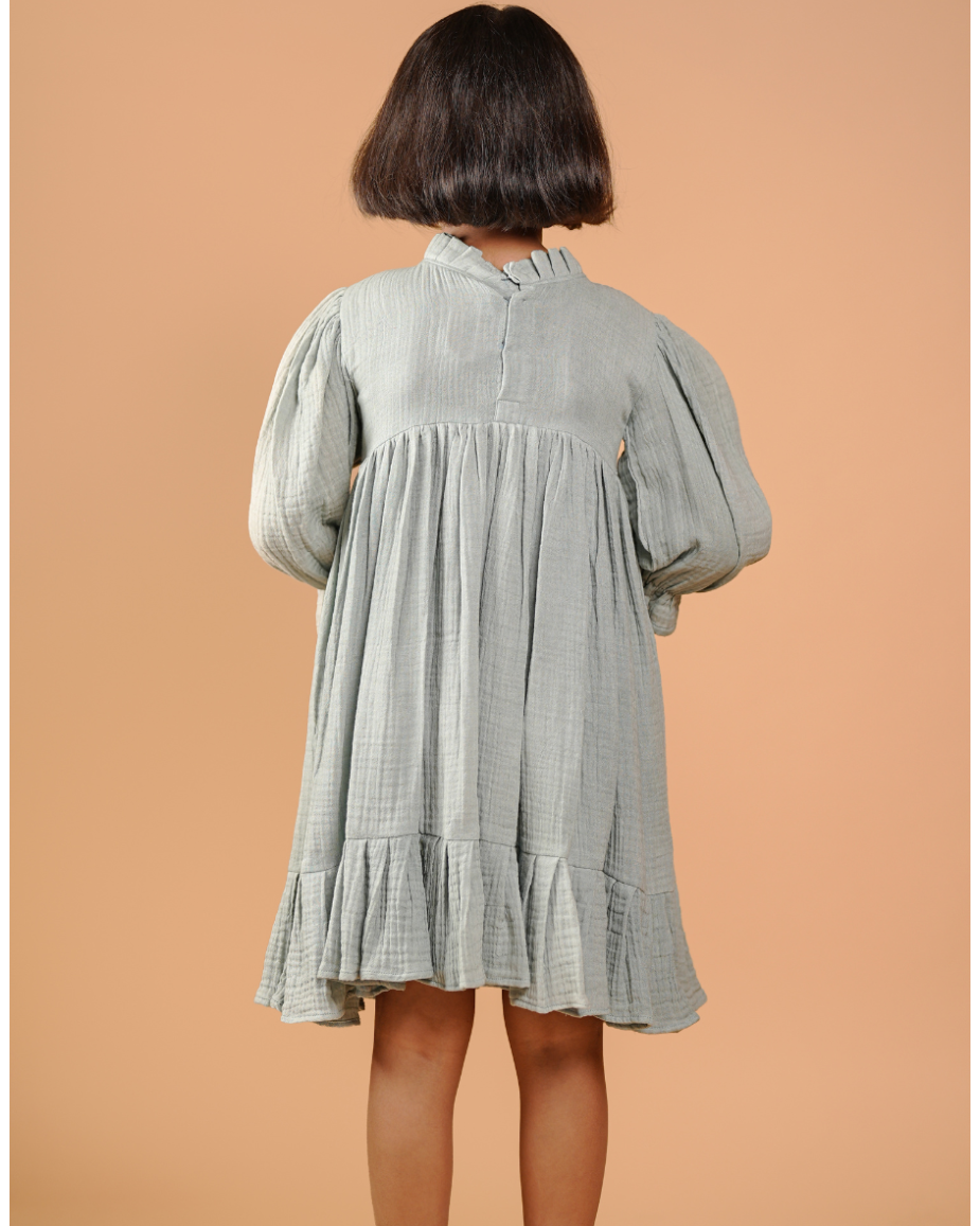 Person wearing a light green checkered dress against a beige background