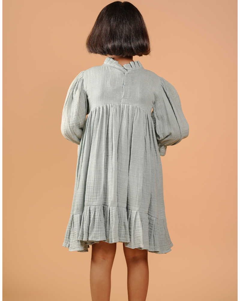 Person wearing a light green checkered dress against a beige background