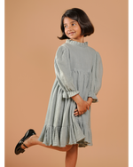 Young girl wearing a light blue dress against a beige background