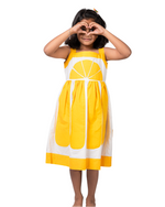 Young girl wearing a yellow dress with a lemon design on a white background