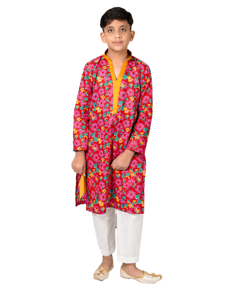 Child wearing a colorful floral kurta with white pants on a white background