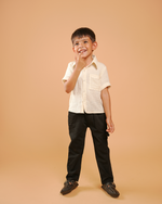 Child wearing a white shirt and black pants on a beige background