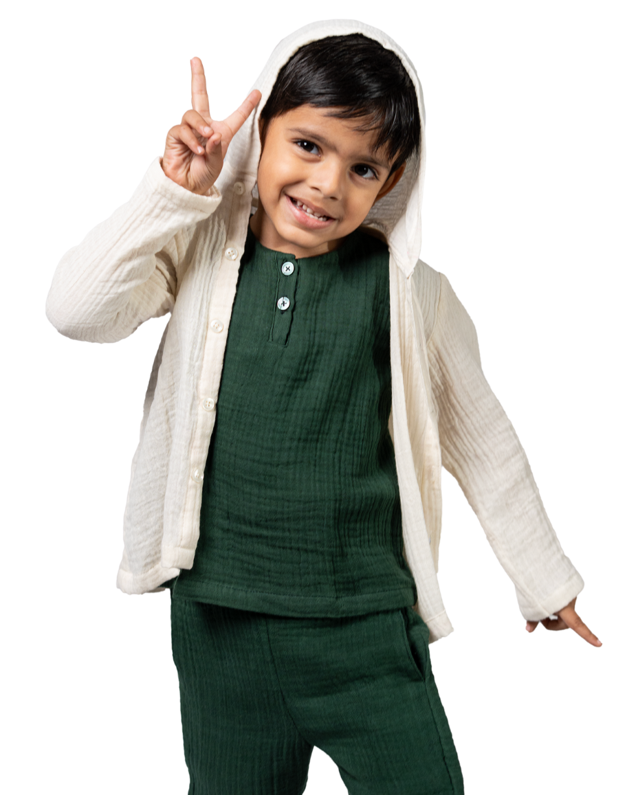Child wearing a green outfit with a white cardigan on a white background