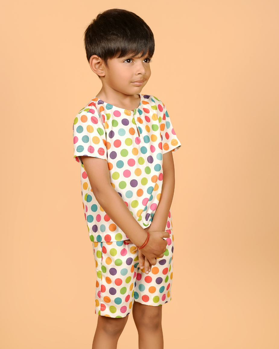 Child wearing a colorful polka dot outfit on a beige background