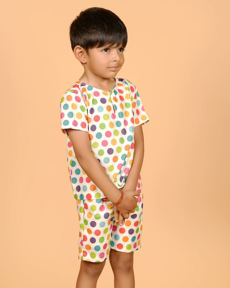 Child wearing a colorful polka dot outfit on a beige background