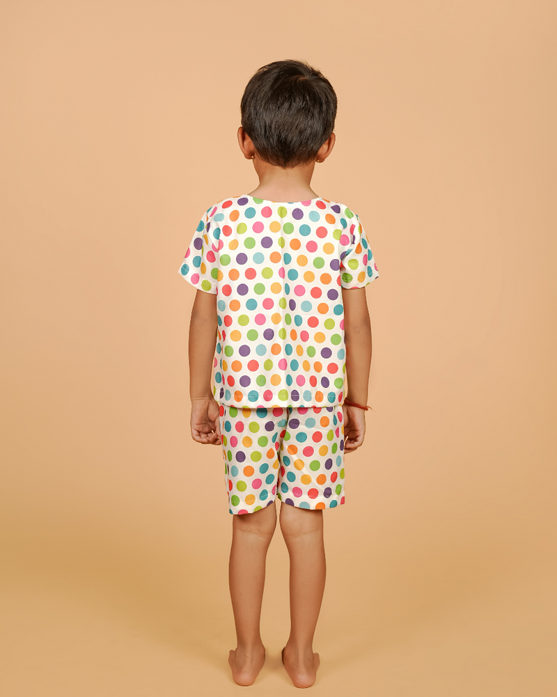 Child wearing a colorful polka dot outfit on a beige background