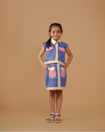 Young girl wearing a blue and pink dress with a vest on a beige background