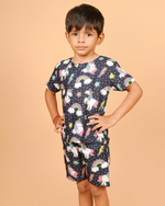 Child wearing a cord set with unicorn and rainbow pattern on a beige background
