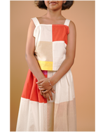 Person wearing a colorful checkered dress against a beige background