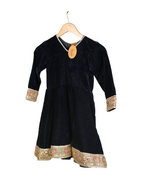 Black traditional outfit with embroidered details on a hanger against a white background