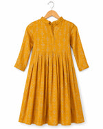 Yellow dress with floral pattern on a hanger against a white background
