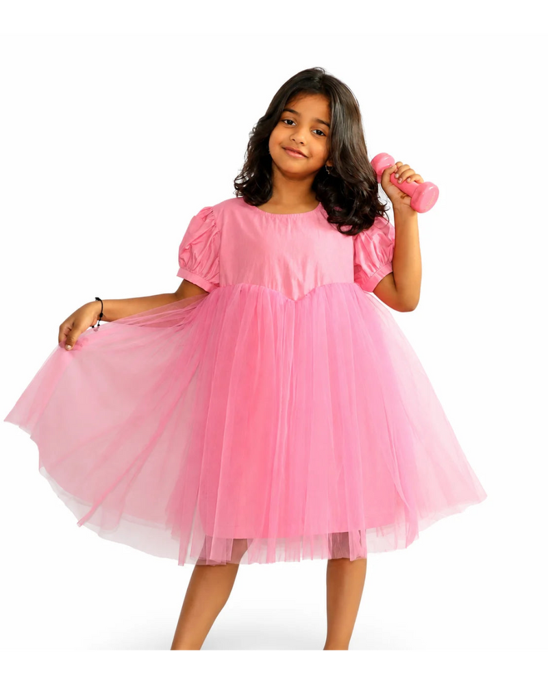 Young girl wearing a pink dress holding a pink toy on a white background