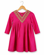 Pink dress with gold embroidery on a hanger against a white background