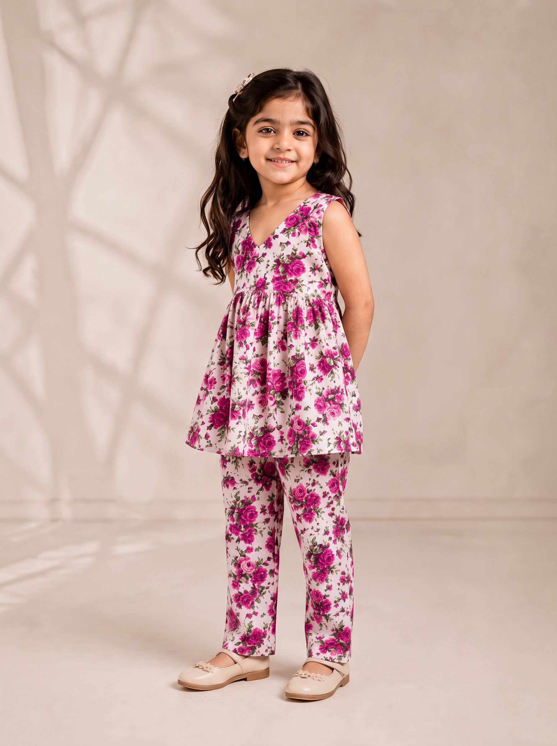 Ameyru Kids Wear girl wearing a sleeveless floral peplum top and matching straight-leg trousers in magenta and white.