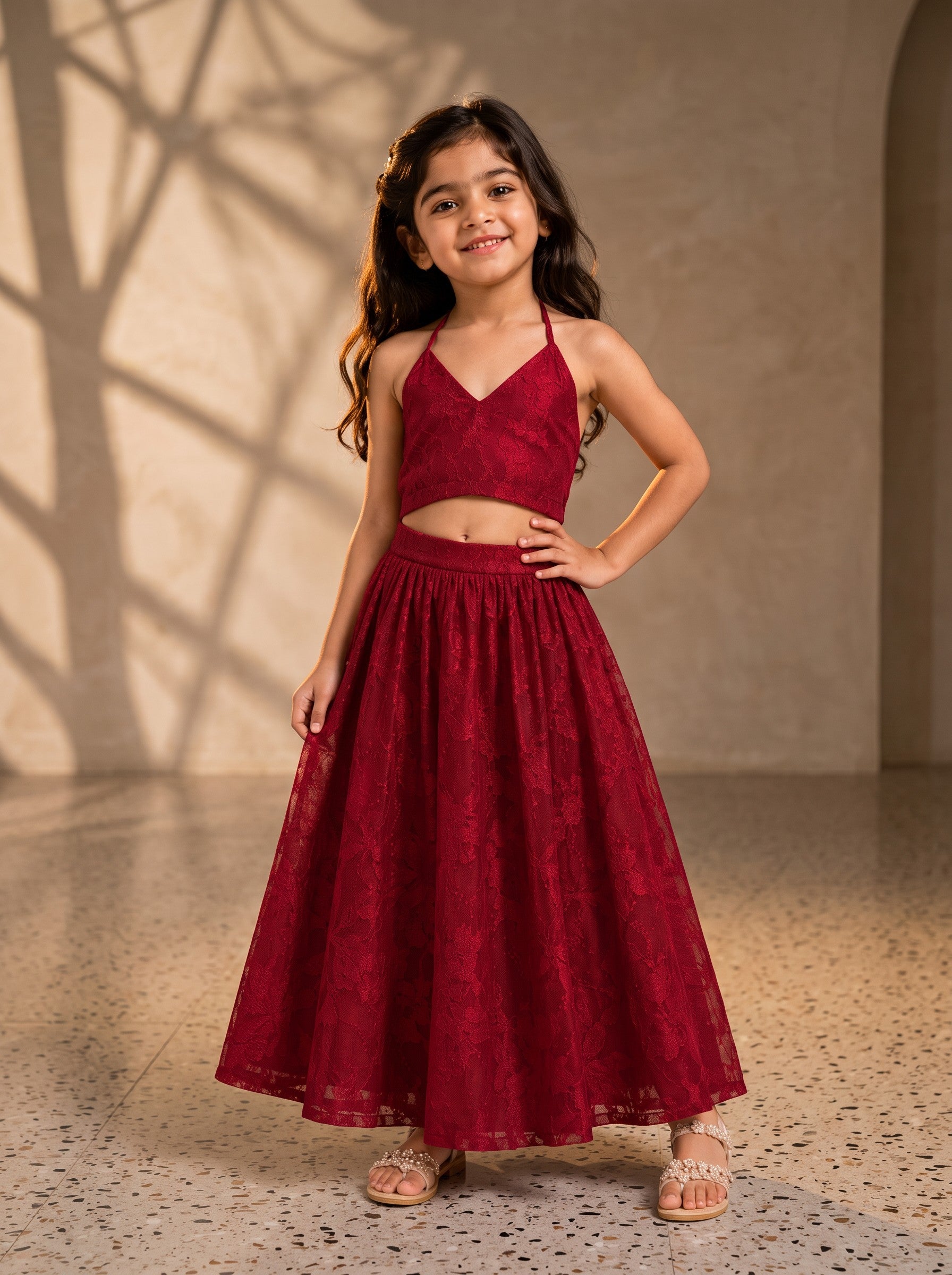 Ameyru Kids Wear girl in a maroon lace two-piece ethnic ensemble with a halter-neck crop top and floor-length skirt.
