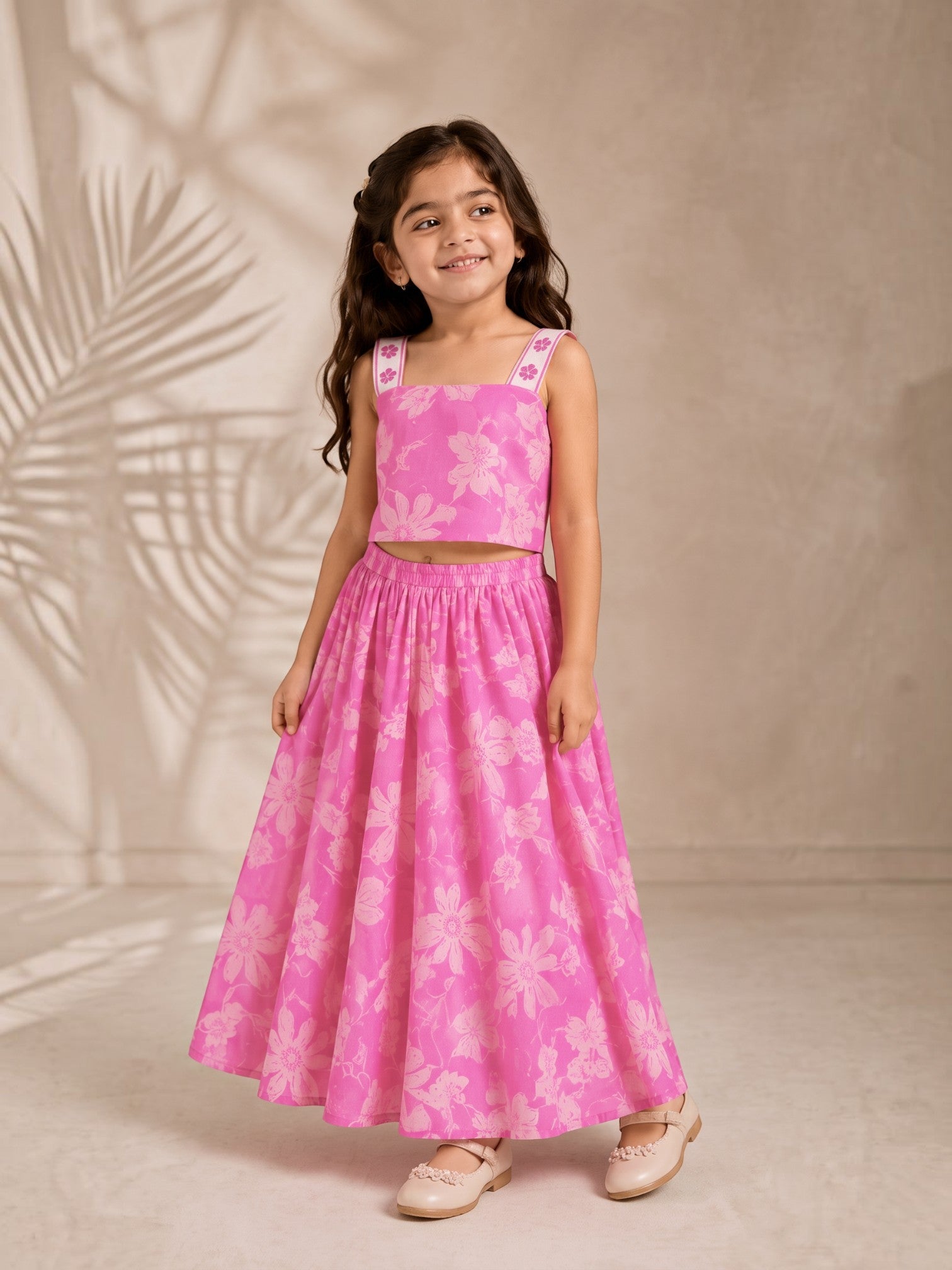 Young girl wearing an Ameyru Kids Wear pink floral crop top and matching floor-length skirt set with wide straps.