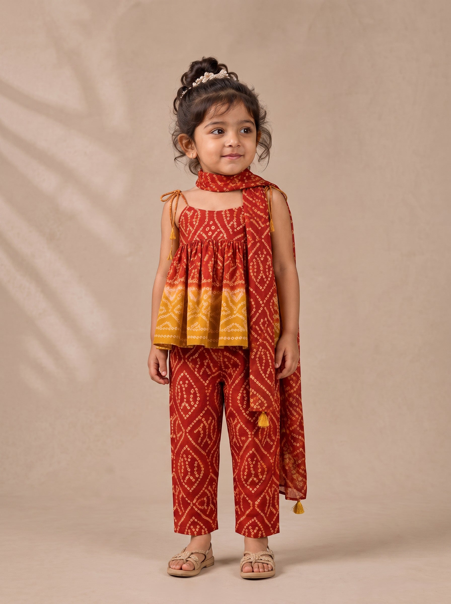 Ameyru Kids Wear red and yellow ethnic bandhani print top and trousers set with a matching scarf on a young girl.