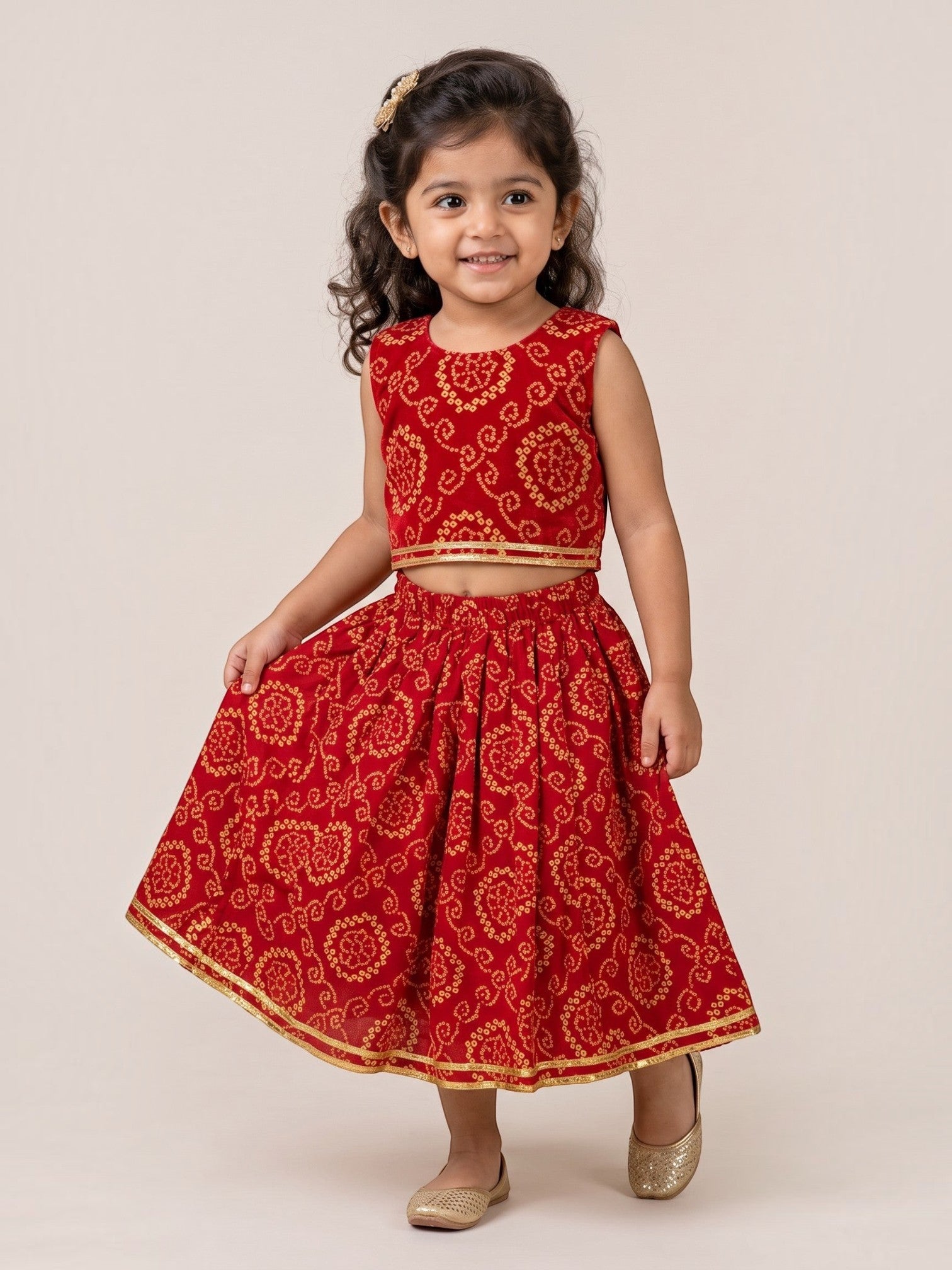Ameyru Kids Wear red ethnic lehenga choli set with gold bandhani patterns and trim on a smiling young girl