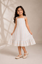 Young girl wearing an Ameyru Kids Wear white cotton dress with colorful vertical stripes and a lace-trimmed hem.