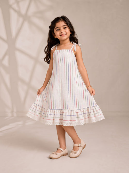 Ameyru Kids Wear girl wearing a white striped sundress with tie straps, ruffle hem, and lace trim.