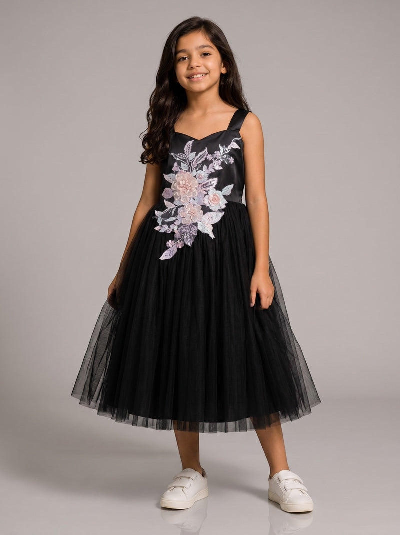 A girl wearing a Baby Kids Cloths black tulle party dress with pastel floral applique embroidery on the bodice.
