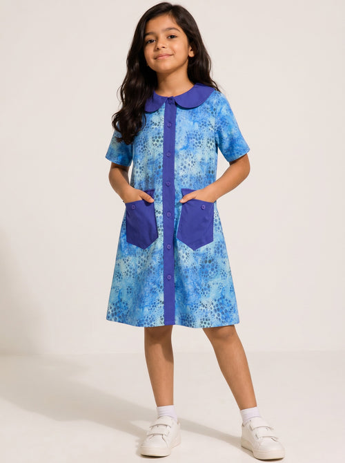 Girl wearing a Baby Kids Cloths blue watercolor dot print A-line dress with a solid collar, button front, and pockets.