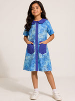 Girl wearing a Baby Kids Cloths blue watercolor dot print A-line dress with a solid collar, button front, and pockets.