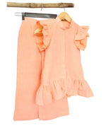 A peach-colored kids' muslin co-ord set with long tunic top and matching loose-fit trousers, displayed on hangers against a white background.